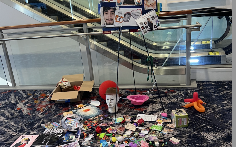 A cardboard image of polka dancers on an escalator surrounded by ribbons and various gifts.